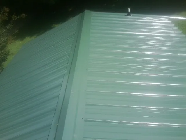 New green metal panels meeting at the ridge of a roof — Flat Roof Repair work by our crew in White Plains
