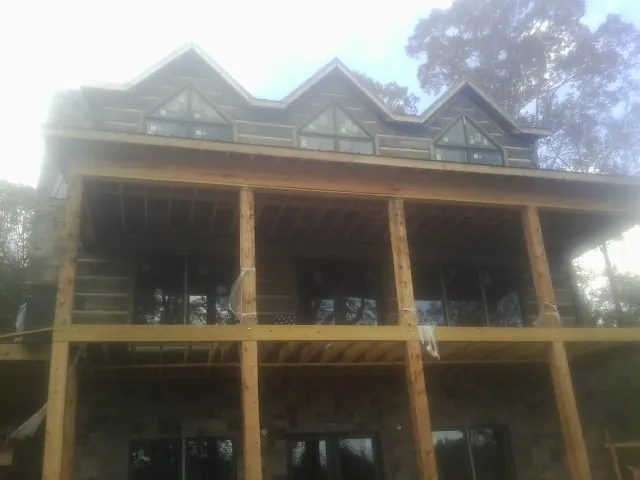 Dormers and porch framing on a large log home under construction — Roof Coating work by our crew in White Plains